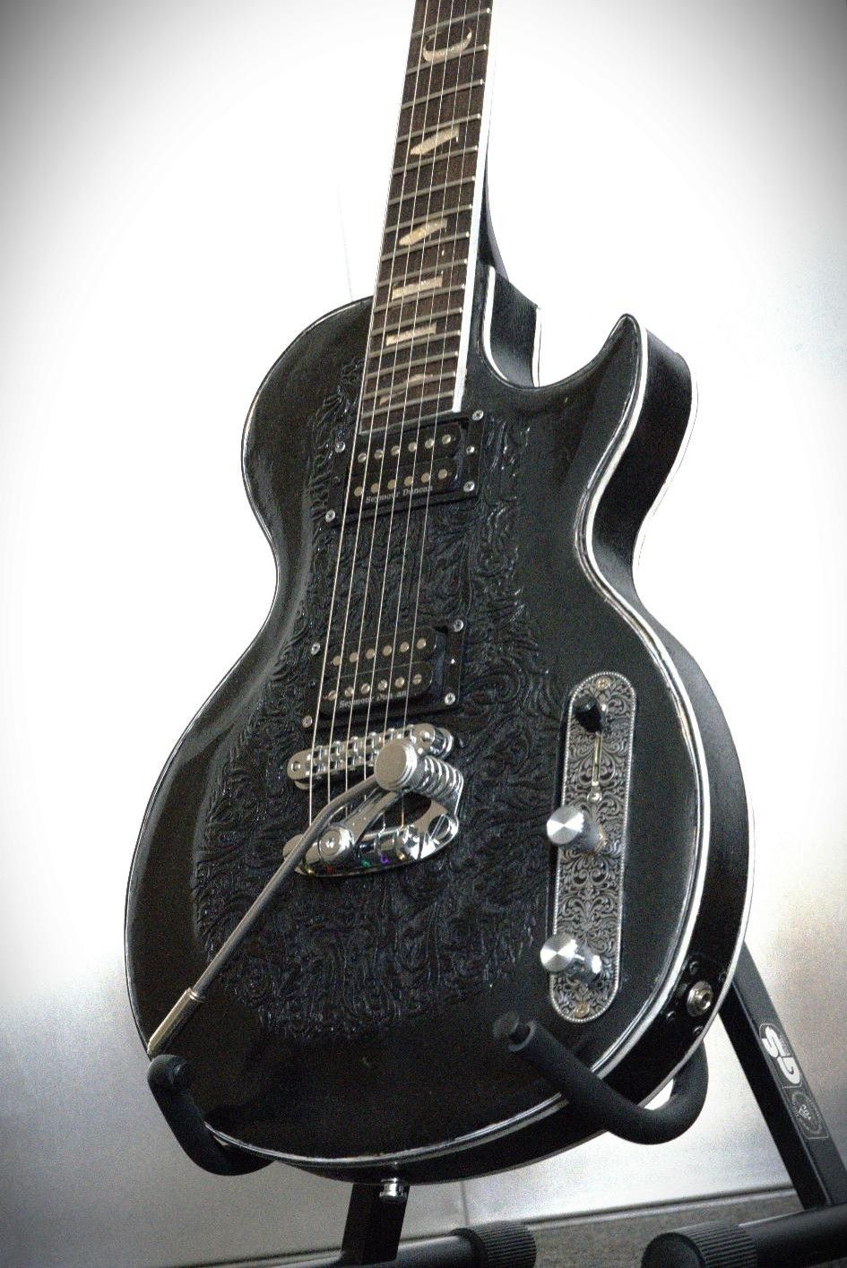 schwarze E-Gitarre mit schwarzen Schnitzereidetails und silberner Hardware 